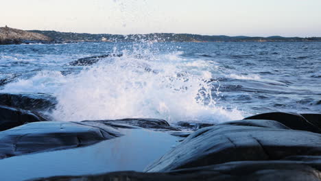 Slow-motion-shot-of-waves-crashing-the-coast-of-the-Justoy-island,-on-the-Skagerrak-sea,-sunny-morning,-in-Aust-Agder,-Norway
