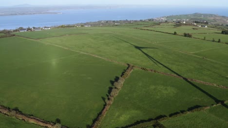 Aerial-of-wind-turbine-shadow-on-green-field-in-Ireland-on-sunny-day