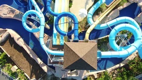 Top-down-view-of-aqua-park-with-water-slides-in-luxury-tropical-vacation-resort,-watersports-and-fun-on-vacation,-aerial-view