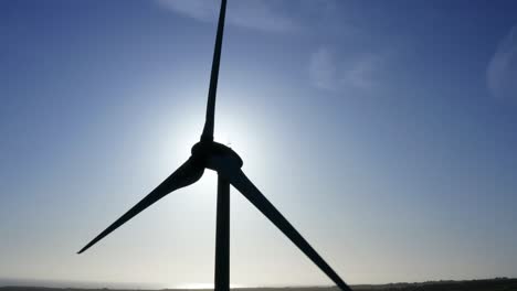 Aerial-static-of-Wind-Turbine,-sun-flare-and-blue-sky-in-background