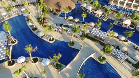 Swimming-pool-area-with-bars-and-bridges-in-romantic,-luxurious-tropical-resort,-upscale-vacation-and-tourism-hotel-in-Dominican-Republic,-idillyc-honeymoon-destination