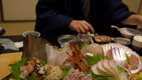 Blick-Auf-Frische-Meeresfrüchte-Im-Traditionellen-Japanischen-Ryokan-Mit-Frau-In-Traditioneller-Kleidung-Im-Hintergrund-Verschwommen