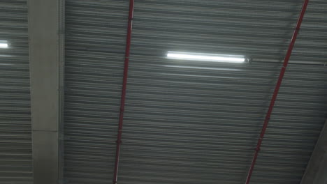 Low-angle-pan-of-fluorescent-lights-hanging-on-industrial-ceiling