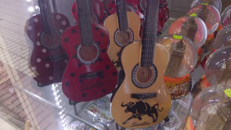 Mini-Spanish-guitar-figurines-in-souvenir-shop-window,-Seville,-Spain