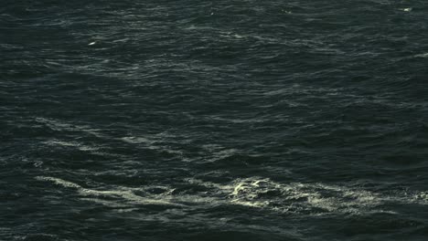 Cinematic-aerial-shot-of-dark-ocean-surface,-moody-sea-waves