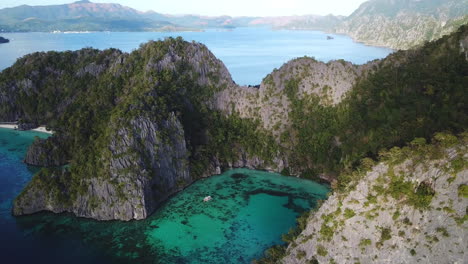 Philippines,-Coron-Island,-Ocean-Cliffs-and-Coral-Reef-Lagoon,-AERIAL-REVEAL