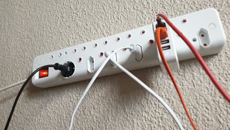 Male-hand-plugging-in-an-electric-USB-phone-and-tablet-charger-into-a-wall-mounted-European-220v-style-multi-plug