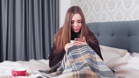girl-reads-about-pills-sitting-on-bed-wrapped-in-plaid
