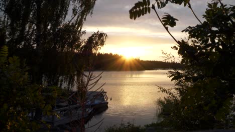 Sunset-over-lake-in-Finland,-Beautiful-Summer-night-scene,-Boat-resting-at-dock