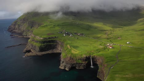 Stunning-coastal-Mulafossur-Waterfall-over-cliffs-in-Faroe-Islands,-aerial-view