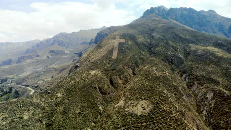 Aerial-Backward-Shot-Of-A-Huge-Handmade-Catholic-Crucifix-On-The-Slope-of-the-Mountain-In-Chivay-Peru
