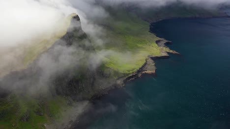 Clouds-rolling-over-tops-of-coastal-cliffs-in-Faroe-Islands,-aerial-reveal