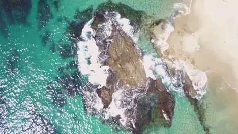 Top-Down-Aerial-View-of-Ocean-Waves-Breaking-on-Rock-and-Victoria-Beach,-Laguna,-California-USA