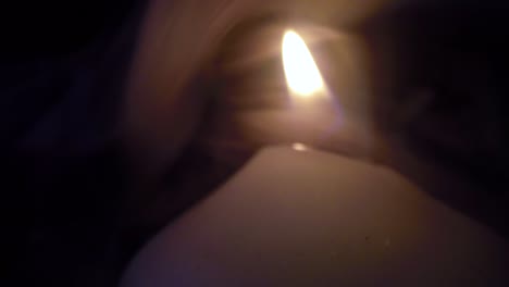 Smoke-surrounding-a-burning-white-candle-close-up-in-a-dark-room