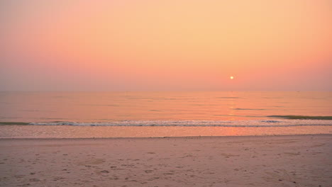 Colorful-ocean-sunset-on-the-beach-with-hazy-sun-in-the-distance