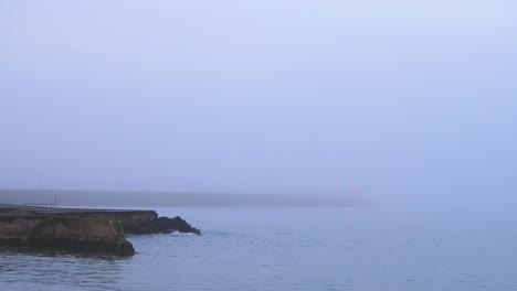 Niebla-Sobre-El-Mar-Y-La-Ciudad-Costera-Al-Amanecer-Con-Aguas-Tranquilas-Y-Cielo-Colorido
