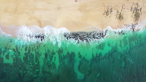 Aerial,-Turquoise-ocean-waves-lap-over-reef-at-Oahu-North-Shore-beach