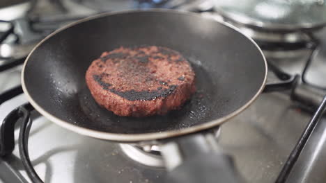 Burned-vegan-plant-based-burger-cooking-on-frying-pan-in-slow-motion