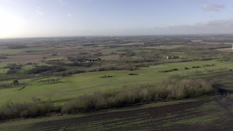Idyllic-British-farming-meadows-countryside-fields-aerial-view-above-rustic-skyline