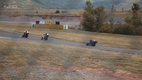 Motocycle-drivers-racing-on-a-track-through-fence