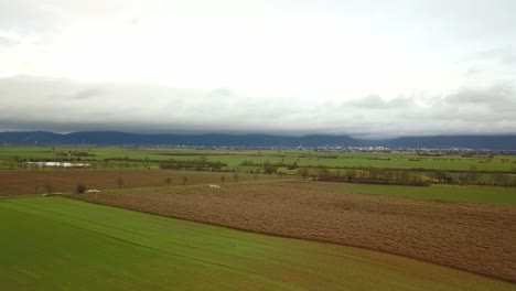 Ascending-over-agriculture-field-with-mountains-in-background-during-autumn-day,-Germany