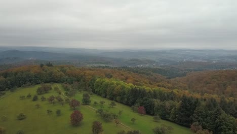 Aerial-view-forward-flying-over-beautiful-mountainous-area-during-fall-day,-Odenwald-Germany