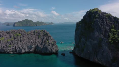 Aerial-drone-rising-above-huge-limestone-cliffs,-turquoise-water-and-natural-archipelago-paradise-in-El-Nido,-Palawan,-Philippines