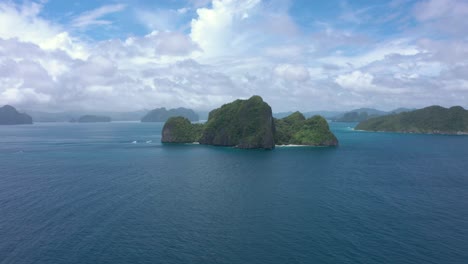 Drone-flying-towards-beautiful-white-sand-secret-beach-with-huge-limestone-cliffs,-turquoise-water,-and-natural-archipelago-paradise-in-El-Nido,-Palawan,-Philippines