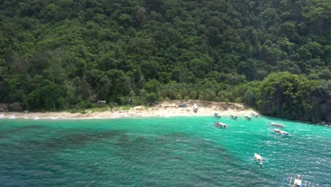 Drohne-Kreist-Um-Einen-Wunderschönen-Weißen-Sandstrand-Mit-Riesigen-Kalksteinfelsen,-Türkisfarbenem-Wasser,-Kleinen-Booten-Und-Einem-Natürlichen-Archipelparadies-In-El-Nido,-Palawan,-Philippinen
