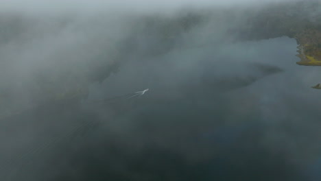 High-flying-drone-shot-looking-over-a-boat-gliding-across-the-Rio-Manso-River-in-Argentina