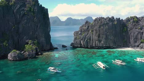 Aerial-circling-around-huge-limestone-cliffs,-turquoise-water-and-natural-archipelago-paradise-in-El-Nido,-Palawan,-Philippines