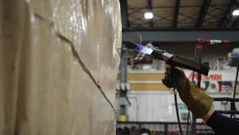Warehouse-worker-using-heat-gun-to-weld-tarpaulin,-slow-motion
