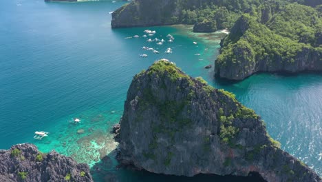 Aerial-drone-circling-around-epic-limestone-cliffs,-turquoise-water-and-natural-archipelago-paradise-in-El-Nido,-Palawan,-Philippines
