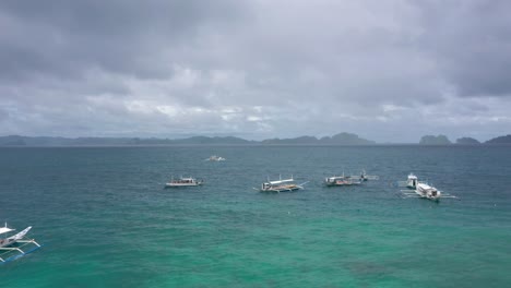 Drohne-Fliegt-über-Kleinen-Fischerbooten-Auf-Türkisfarbenem-Wasser-Und-Natürlichem-Archipelparadies-In-El-Nido,-Palawan,-Philippinen