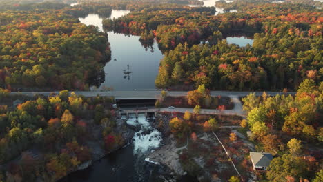 Aerial-orbiting-view,-tranquil-scenery-of-Lake-running-through-dam,-autumnal-foliage-landscape,-Vaughan