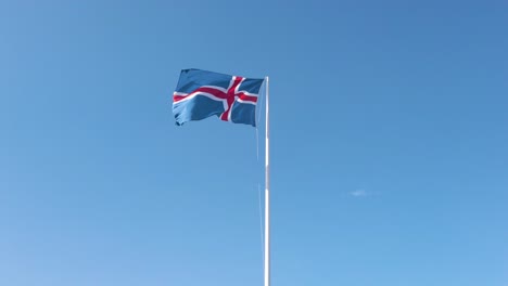 Aerial-shot-of-Iceland-flag-waving-in-the-with-blue-sky-background