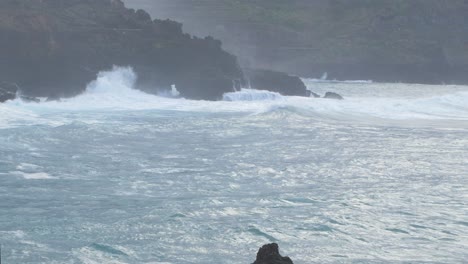 A-big-waves-of-the-Atlantic-Ocean-breaks-on-a-rocky-coast-on-a-sunny-day-during-a-storm-in-Puerto-de-la-Cruz-in-the-Canaries-,-medium-wide-shot