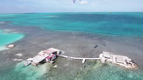 Aerial-view-MAN-JUMP-on-WOODEN-old-Pier-from-stilt-house-PALAFITO-LOS-ROQUES-Venezuela
