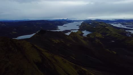Aerial-landscape-view-of-Icelandic-highlands,-dark-mountain-peaks,-rivers-and-lakes,-on-a-cloudy-day