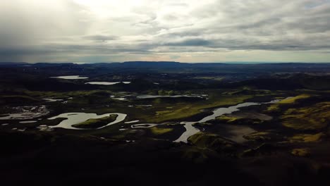 Aerial-landscape-view-of-Icelandic-highlands,-dark-hills-and-mountains,-rivers-and-lakes,-on-a-cloudy-day