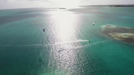 Sonnenuntergang-Zwei-Kiteboard-Fahrer-überqueren-Bluewater-Sea,-Luftaufnahme-Los-Roques
