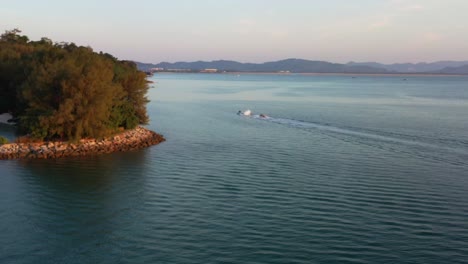 Cinematic-aerial-drone-chasing-and-following-behind-a-jet-ski-pulling-a-banana-boat-ride,-water-sport-activity-in-Langkawi-island,-Kedah,-Malaysia,-Southeast-Asia