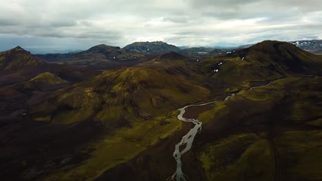 Aerial-landscape-view-of-Icelandic-highlands-with-snow-capped-mountain's-peaks,-and-a-river-flowing