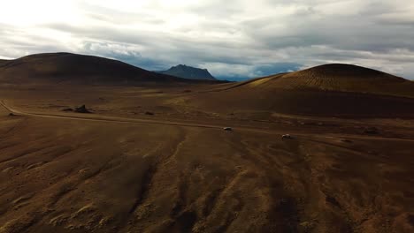 Aerial-landscape-view-over-four-wheel-drive-cars-traveling-on-a-dirt-road-in-the-icelandic-highlands