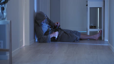 Drunk-man-dressed-in-hooded-bathrobe-lying-on-floor