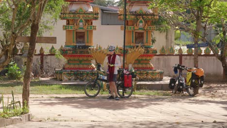 Junge-Asiatische-Radfahrerin,-Die-Sich-Beim-Mittagessen-In-Einem-Tempel-Auf-Der-Straße-In-Laos-Ausruht