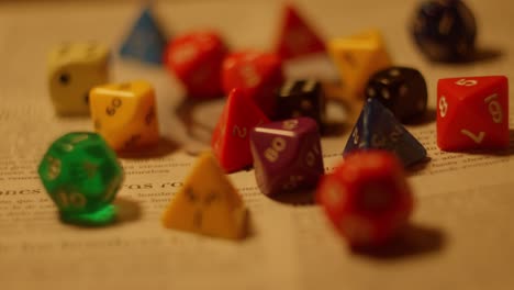 Variety-of-colorful-board-game-dices-laying-on-role-book,-slider-shot