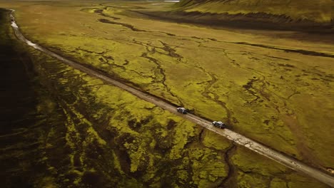 Aerial-landscape-view-over-two-four-wheel-drive-cars-traveling-on-a-dirt-road-through-icelandic-highlands