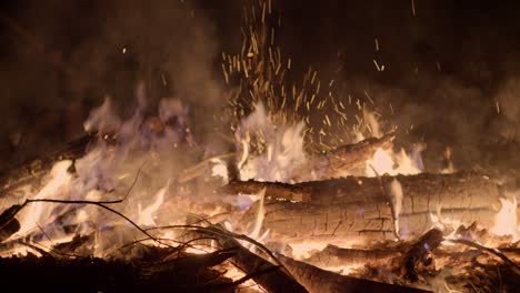 Close-up-shot-of-logs-of-wood-burning-on-a-cold-winter-night-with-open-flames-rising-up-at-a-Christmas-market-winter-wonderland