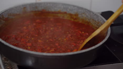 Revolviendo-La-Salsa-De-Tomate-Burbujeante-Con-Una-Cuchara-De-Madera
